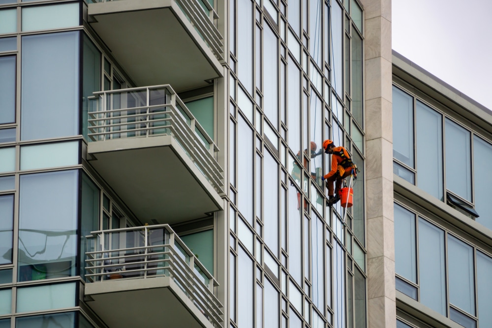 Glazenwasser Appartementencomplex tijdens glasbewassing met veilige werkzone